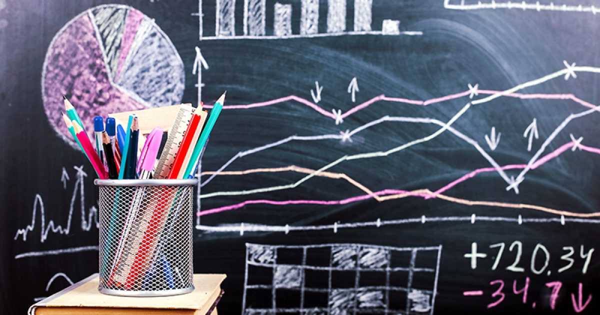 Books on the table against the background of chalkboard on which are drawn graphs and charts of growth and decline. Business training school.